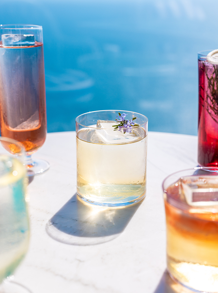 Some cocktails on a table with the sea in the background.