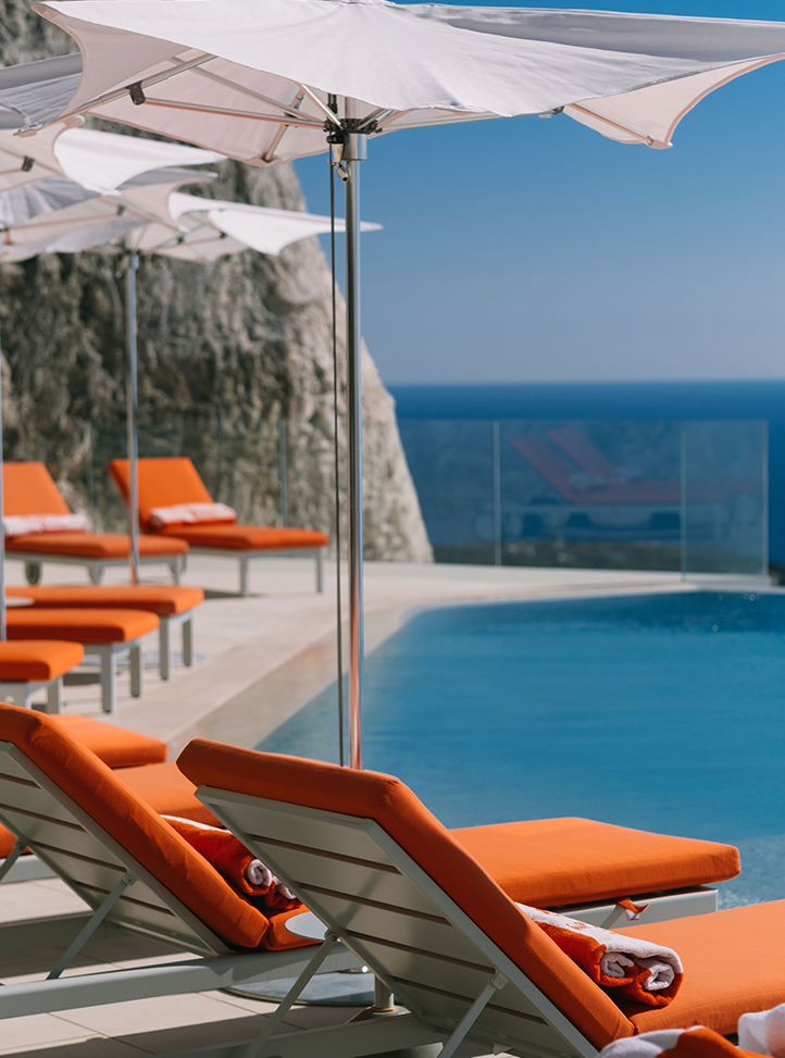 La piscine du Maybourne Riviera avec des transats orange et un parasol blanc.